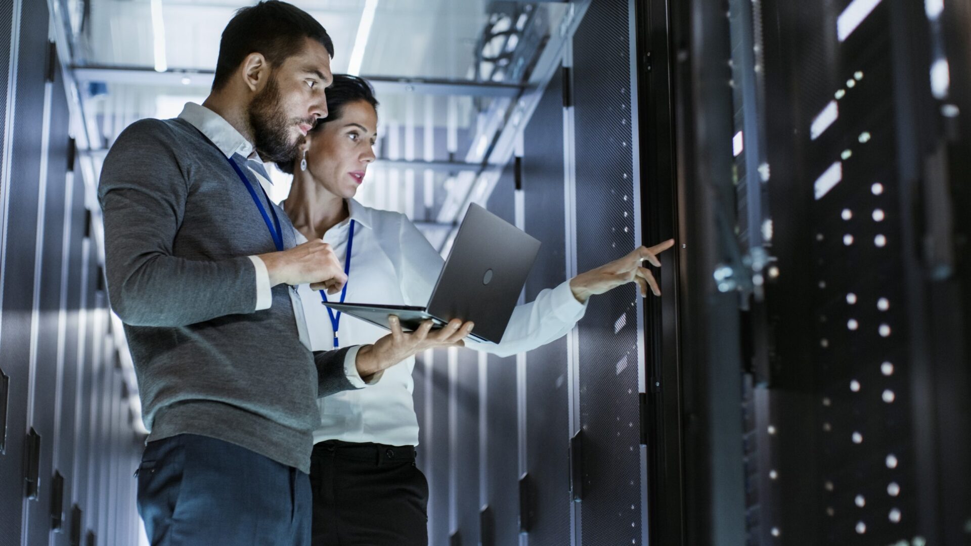 Two engineers dealing with network management issues at a server rack in a data center